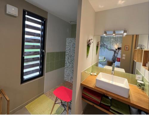 ein Badezimmer mit einem weißen Waschbecken und einem roten Stuhl in der Unterkunft Relais de La Brande in Saint-Gourson
