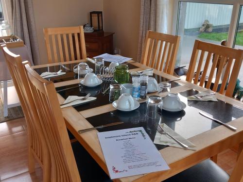 a dining room table with chairs and a wooden table with plates and dishes at Inishmore Island B&B in Inishmore