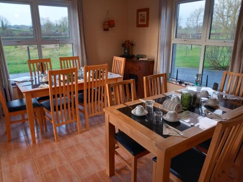 uma sala de jantar com mesas, cadeiras e janelas em Inishmore Island B&B em Inishmore