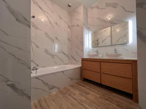 La salle de bains est pourvue d'un lavabo, d'une baignoire et d'un miroir. dans l'établissement Appartement château de Lewarde, à Douai