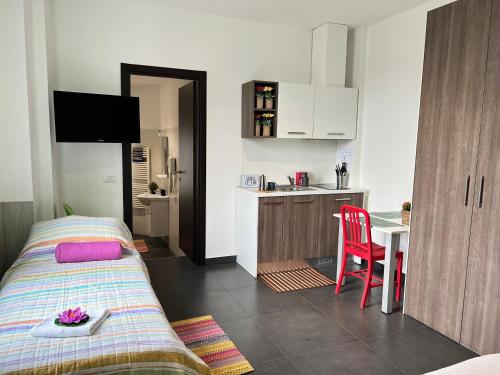 a bedroom with a bed and a table and a kitchen at Bnbook Residence Matteotti in Novara