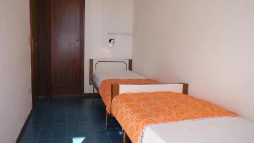 una camera con tre letti con lenzuola arancioni e una porta di Villetta Ariosto a Lido delle Nazioni