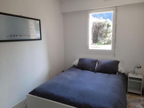 um quarto com uma cama azul e uma janela em Ty Cocoon- Appartement avec terrasse et parking privé em Quimper