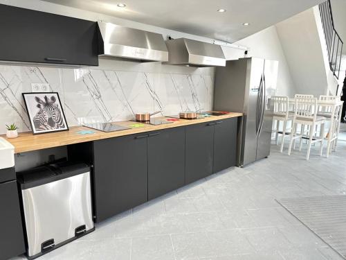 uma cozinha com armários pretos e um frigorífico de aço inoxidável em "Silk & Suites" City Center em Saint-Étienne