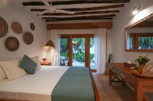 a bedroom with a bed and a table and a mirror at Villa Tulia in Matemwe