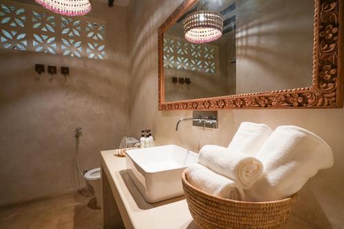 a bathroom with a sink and a mirror and towels at Villa Tulia in Matemwe