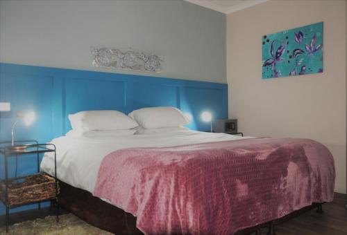 a bedroom with a large bed with blue walls at Courtyard@Saxon in Gansbaai