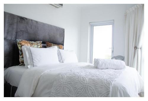 a bedroom with a white bed with a large window at St Clouds Strand in Strand