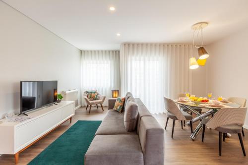 a living room with a couch and a tv and a table at Flamingo Apartment in City Center - Minho's Guest in Braga