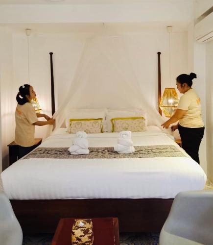 two women standing next to a bed in a room at Moonlight Champa Riverview in Luang Prabang