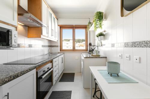cocina blanca con fregadero y encimera en Nazaré Modern Flat, en Nazaré