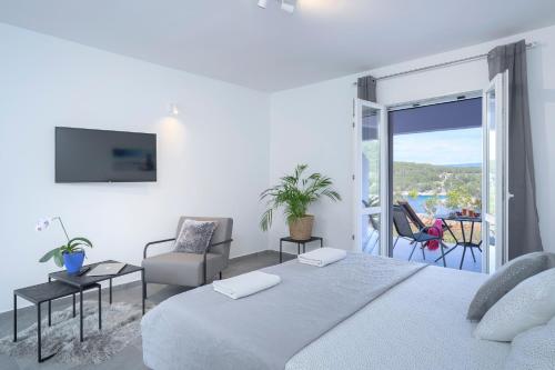 a white bedroom with a large bed and a balcony at Villa Serenity in Hvar