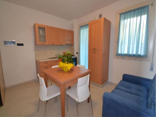 uma cozinha com uma mesa de madeira e cadeiras brancas em Modern flat with private garden in Rosolina Mare em Rosolina Mare