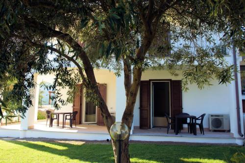 a tree in front of a house with a table and chairs at Sa Fiorida Appartamenti in Valledoria
