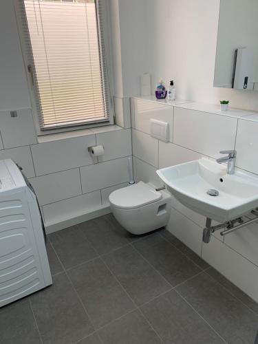 ein weißes Bad mit einem WC und einem Waschbecken in der Unterkunft Apartment 70 qm Kalimandscharo 3 in Zielitz - Magdeburg in Zielitz