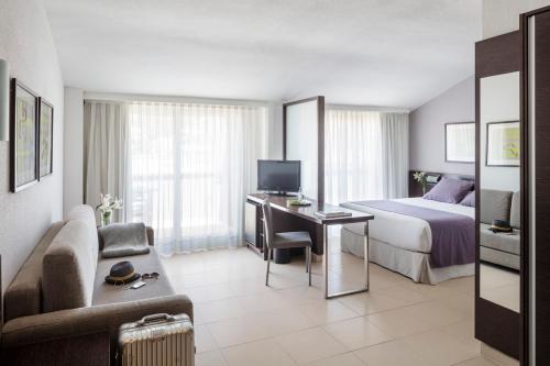 a hotel room with a bed and a desk with a television at AQUA Hotel Montagut Suites 4*Sup in Santa Susanna