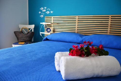 Una cama azul con una toalla y flores. en B&B Vivere il Mare, en San Vito lo Capo