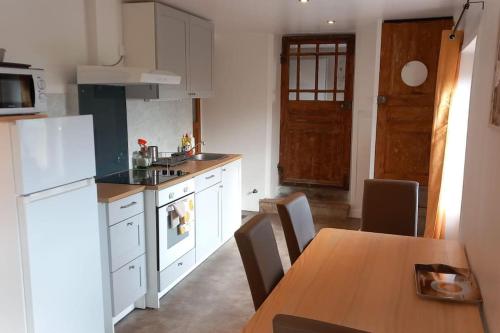 a kitchen with a table and a white refrigerator at Joli appartement Les Archers in Montpeyroux