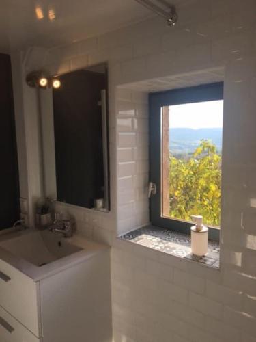 La salle de bains est pourvue d'un lavabo et d'une fenêtre avec vue. dans l'établissement Joli appartement Les Archers, à Montpeyroux