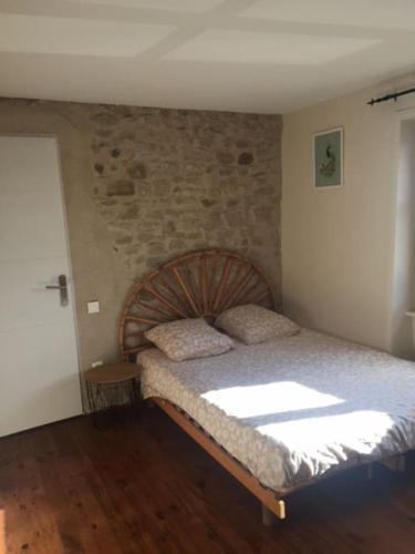 une chambre avec un lit et un mur en pierre dans l'établissement Joli appartement Les Archers, à Montpeyroux