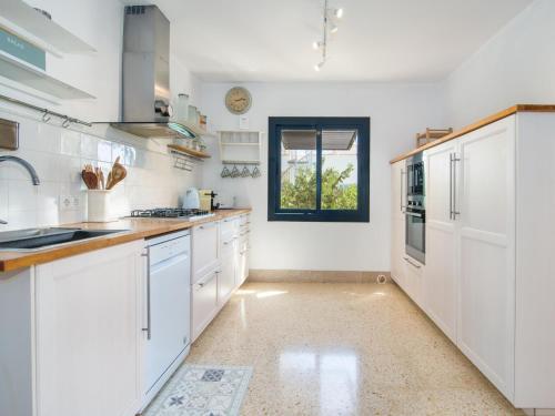 a kitchen with white cabinets and a window at Casa Lloc Tranquil in Cala Figuera