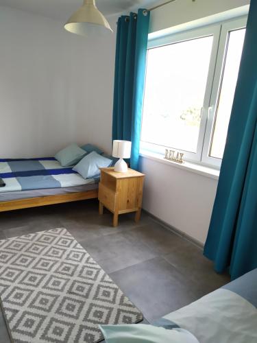 a bedroom with a bed and a window with blue curtains at #WilkasyPortPlaża in Wilkasy