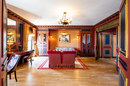 a living room with a red couch and a piano at InterContinental Bordeaux Le Grand Hotel by IHG in Bordeaux