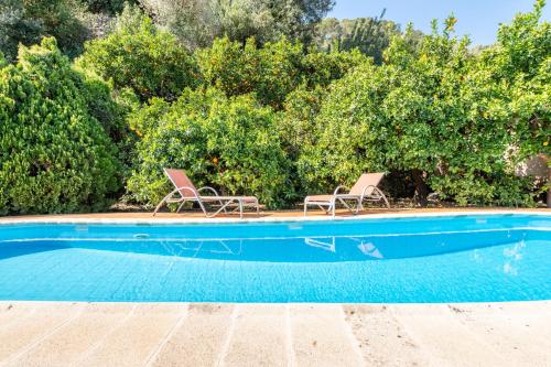 two chairs and a swimming pool with trees at Can Jaumins in Sóller