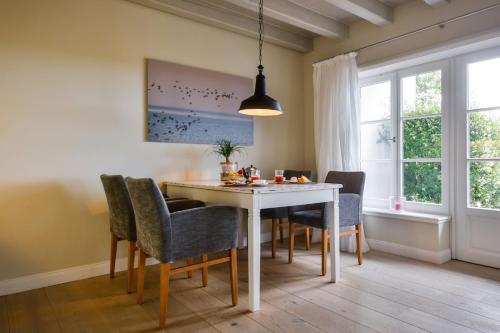 a dining room with a white table and chairs at Kontorhaus Keitum in Keitum
