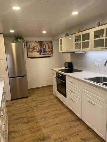 una cucina con armadi bianchi e frigorifero in acciaio inossidabile di Apartment Chalet Im sunnigen Usblick a Wengen
