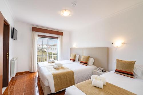 a bedroom with two beds and a window at Hotel Padre Pio by Umbral in Fátima