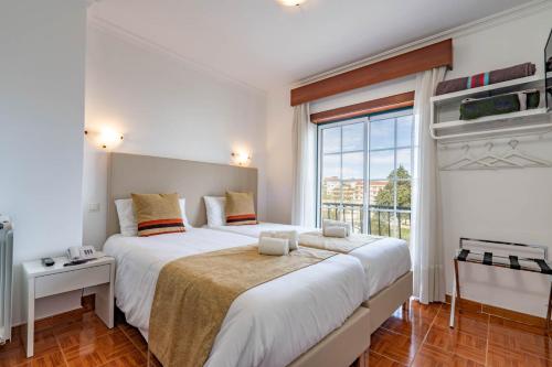 a bedroom with a large bed and a large window at Hotel Padre Pio by Umbral in Fátima