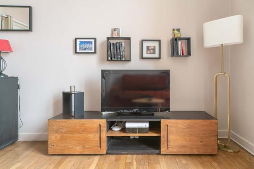 - un salon avec une télévision sur un centre de divertissement en bois dans l'établissement Le larbaud - Appartement calme et lumineux en centre ville, à Vichy