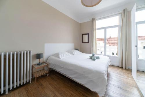une chambre blanche avec un lit et une fenêtre dans l'établissement Le larbaud - Appartement calme et lumineux en centre ville, à Vichy