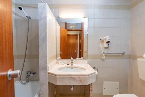 a bathroom with a sink and a toilet and a mirror at Villa Fatima Hotel by Umbral in Fátima