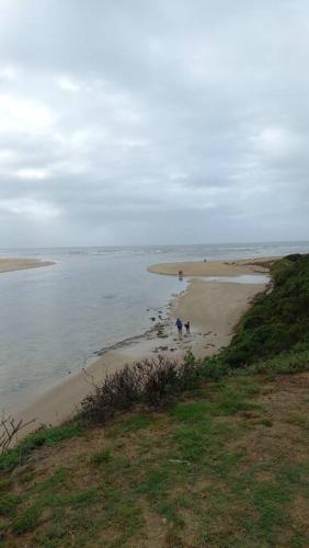 a beach with people walking on the sand and the water at Superb accommodation in Stilbaai in Stilbaai