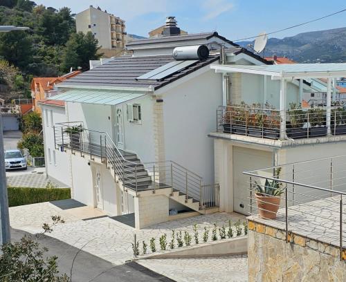 ein weißes Haus mit einer Seitentreppe in der Unterkunft Apartmani Barnjak in Trogir