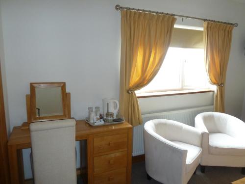 Habitación con espejo, silla y escritorio. en Gwynfryn Guest House, en Pembrokeshire