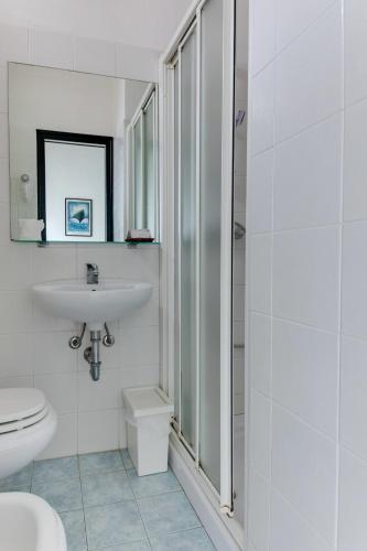 a white bathroom with a sink and a toilet at Hotel Villa Merope in Rimini