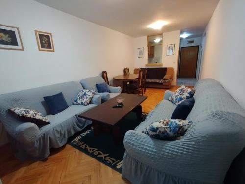 Apartment in Budva في بودفا: غرفة معيشة مع كنبتين زرقاوين وطاولة
