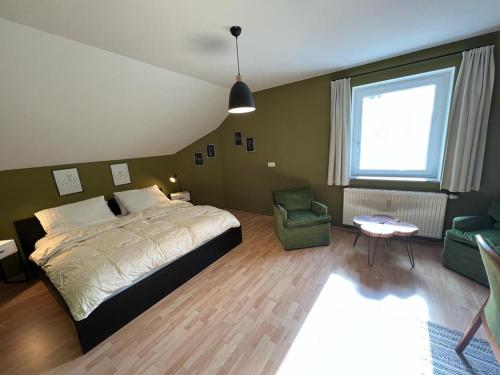 ein Schlafzimmer mit einem Bett, einem Sofa und einem Stuhl in der Unterkunft Ferienwohnungen Pesenbachtal in Herzogsdorf