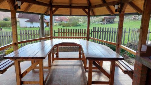 een houten picknicktafel in een paviljoen met een hek bij Vikendica Obradović in Perućac