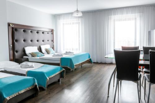 a hotel room with two beds and a table and chairs at Hotel Opera in Tarnowskie Góry