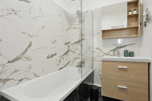 a bathroom with a tub and a marble wall at Le Berthier - Versailles in Versailles