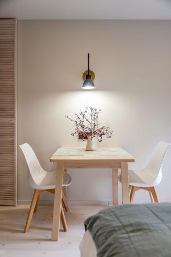 a table with two chairs and a vase with flowers on it at B2 Apartments in Klaipėda