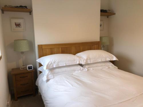 Una cama con sábanas blancas y almohadas en un dormitorio en Aga Cottage, 