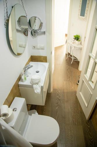 a white bathroom with a sink and a mirror at Alojamientos Puerta Palma con vistas y Parking in Badajoz