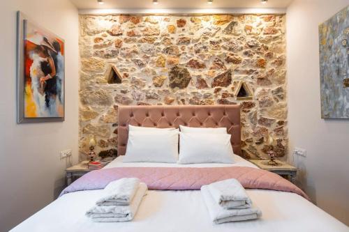 a bedroom with a stone wall and a large bed at Queen's stone legend, royal living by Acropolis in Athens
