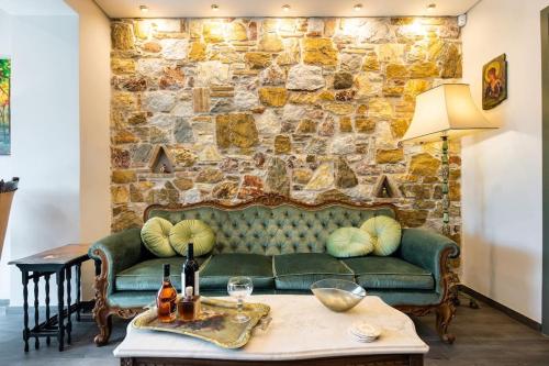 a living room with a green couch and a stone wall at Queen's stone legend, royal living by Acropolis in Athens