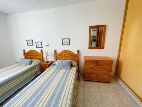 1 dormitorio con 2 camas, tocador y espejo en Torres del Sol, en Playa de las Américas